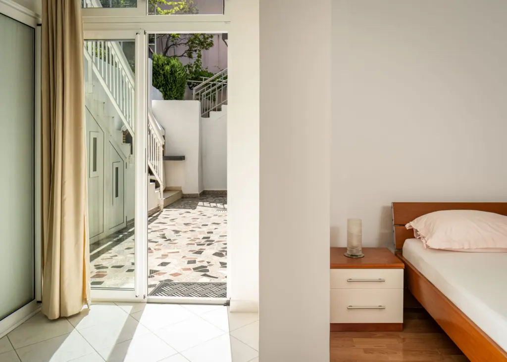 Staklena vrata apartmana prema dvorištu s kamenim mozaikom i stubama