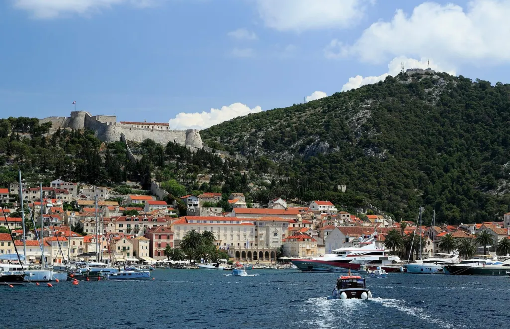 Grad Hvar viđen s mora: luka s jedrilicama i jahtama, glavni trg i tvrđava Španjola na brdu