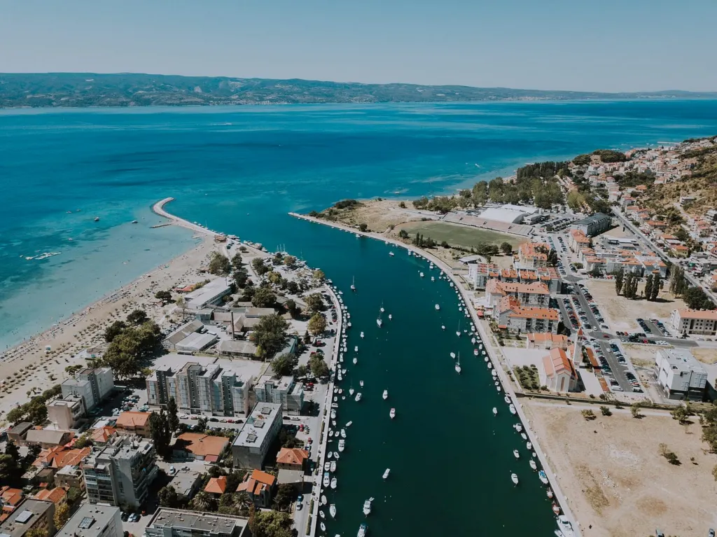 Ušće rijeke Cetine u Omišu iz zraka: rijeka s brodicama, pješčana plaža i Jadransko more